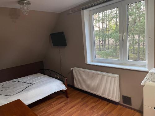 a small bedroom with a bed and two windows at Ptasi dół in Sulęczyno