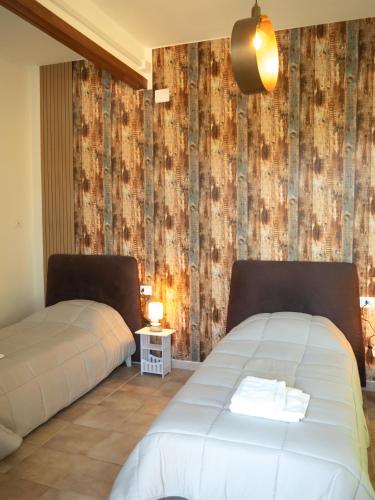 two beds in a room with a wall covered in wood at Affittacamere DaME in Foligno