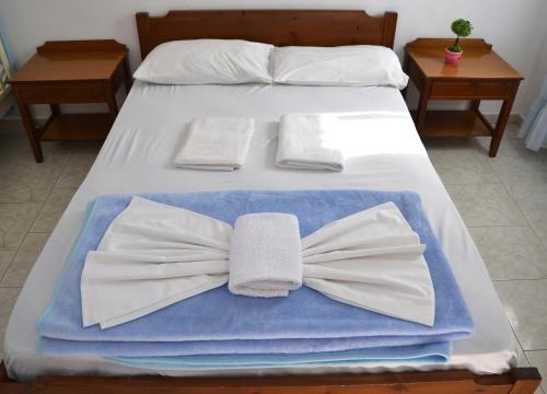 a bed with white towels and a bow tie on it at Orthi Ammos in Frangokastello