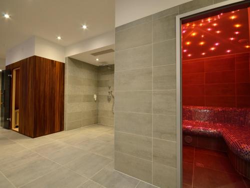 uma casa de banho com um chuveiro e uma parede vermelha em Aparthotel Miramare em Makarska