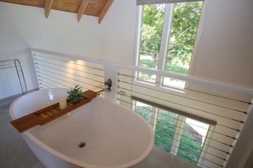 a bathroom with a large white tub and two windows at Bonnie's Cottage - Peaceful retreat in Wandiligong
