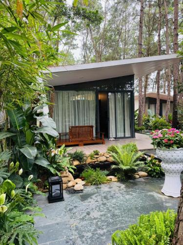 a small house with a bench in a garden at Biệt Thự chủ nhà tự doanh tại FLAMINGOS ĐẠI LẢI RESORT in Phúc Yên