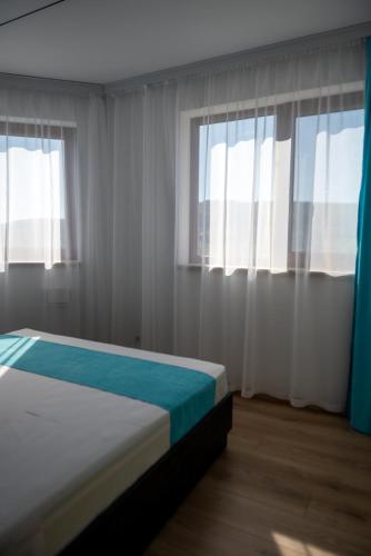 a bedroom with white curtains and a bed with blue sheets at Queen's Penthouse Balchik apartment in Balchik