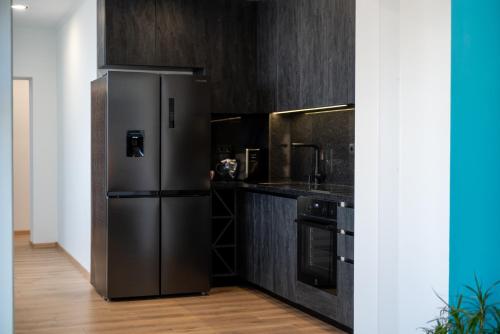 a stainless steel refrigerator in a kitchen with black cabinets at Queen's Penthouse Balchik apartment in Balchik