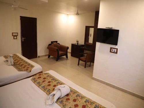a hotel room with two beds and a flat screen tv at Hotel Drive Inn in Haridwār
