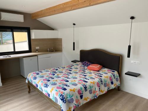 a bedroom with a bed with a colorful comforter at Studio indépendant dans propriété au cœur du Beaujolais in Lachassagne