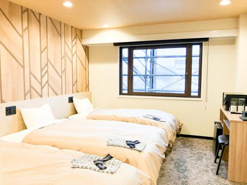 two beds in a room with a window at HOTEL LiVEMAX Toyooka in Toyooka