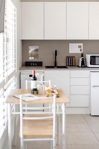 a kitchen with a wooden table and white cabinets at Mala Retreat Sleeps 7, Two Bedrooms & Ensuites in East Maitland