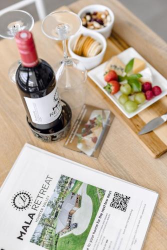 a table with a bottle of wine and a plate of fruit at Mala Retreat Sleeps 7, Two Bedrooms & Ensuites in East Maitland