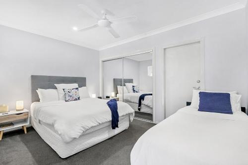 a white bedroom with two beds and a mirror at Mala Retreat Sleeps 7, Two Bedrooms & Ensuites in East Maitland