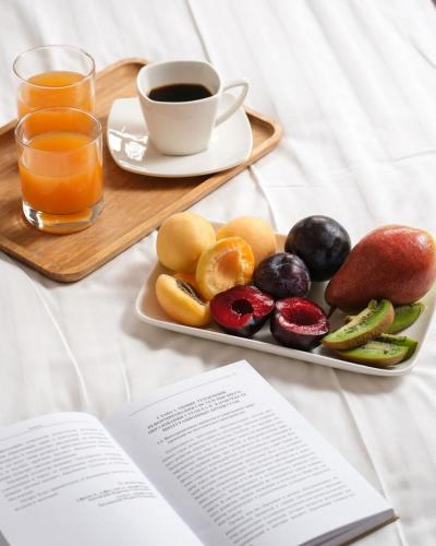 a plate of fruit and a cup of coffee and a book at Skyline Hotel Yerevan in Yerevan