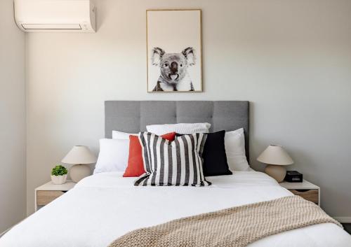 a bedroom with a white bed and a picture of a dog at Mala Retreat Sleeps 7, Two Bedrooms & Ensuites in East Maitland