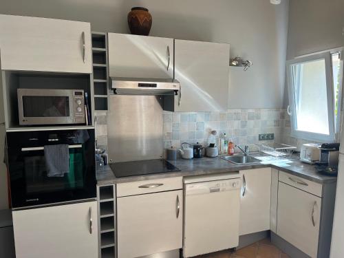 une cuisine avec des armoires blanches et un micro-ondes dans l'établissement Petit lupin de l’estuaire, à Saint-Nazaire-sur-Charente