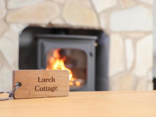 a wooden sign that reads earth college sitting on a table in front of a fire at Larch in Newtonmore
