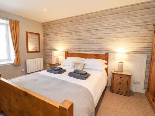 a bedroom with a bed with two blue towels on it at Larch in Newtonmore