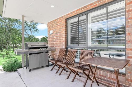 a patio with a barbecue and a wooden table and chairs at Mala Retreat Sleeps 7, Two Bedrooms & Ensuites in East Maitland