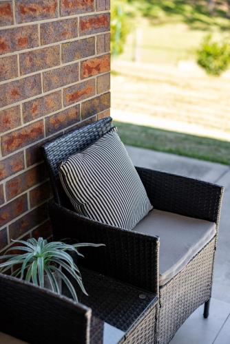 a wicker chair sitting next to a brick wall at Mala Retreat Sleeps 7, Two Bedrooms & Ensuites in East Maitland