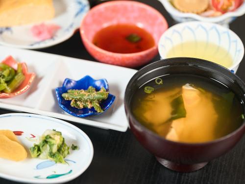 a table with a bowl of soup and plates of food at Sinonomesou Kinosaki Onsen in Toyooka