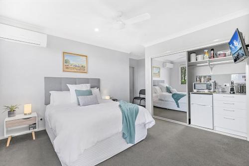a white bedroom with a large bed and a mirror at Mala Retreat Sleeps 7, Two Bedrooms & Ensuites in East Maitland