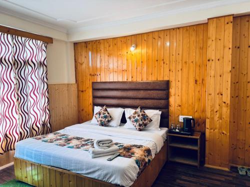 a bedroom with a bed with a wooden wall at Hotel Suraj Inn ,near Hadimba Devi Temple ! Rooftop Restaurant ! Personal Parking in Manāli