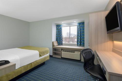 a small hotel room with a bed and a television at Microtel Inn by Wyndham Lake Norman in Cornelius