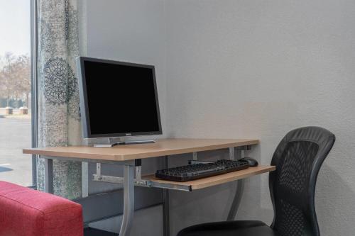 a desk with a computer monitor and a keyboard at Microtel Inn by Wyndham Lake Norman in Cornelius