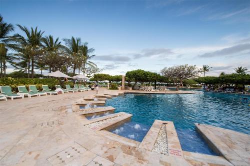 a large swimming pool with chairs and trees in a resort at Grand Hyatt Bali in Nusa Dua
