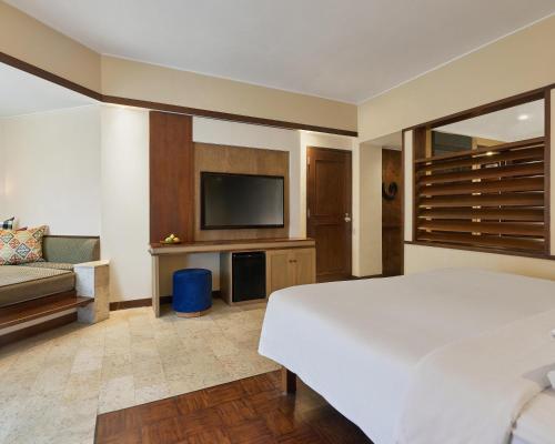 a bedroom with a bed and a tv and a couch at Grand Hyatt Bali in Nusa Dua