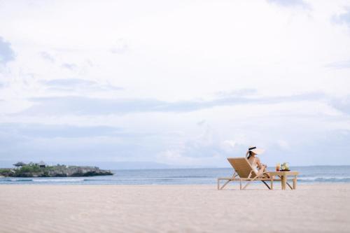 a woman sitting in a chair on the beach at Grand Hyatt Bali in Nusa Dua