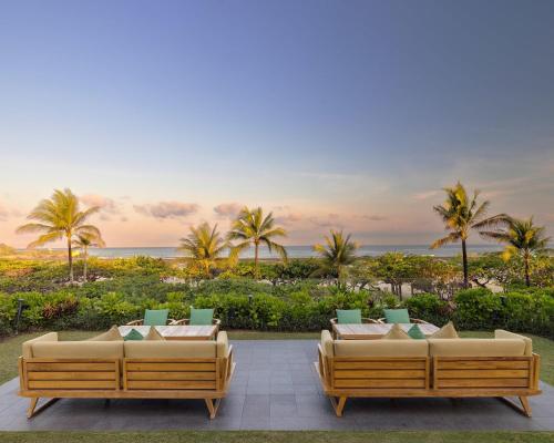 two couches on a patio with palm trees and the ocean at Grand Hyatt Bali in Nusa Dua