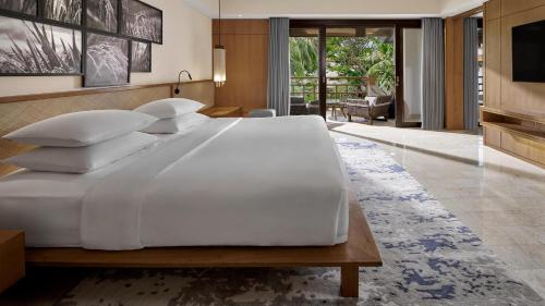 a large white bed in a room with a television at Grand Hyatt Bali in Nusa Dua