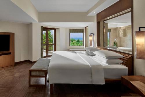 a bedroom with a large white bed and a large window at Grand Hyatt Bali in Nusa Dua