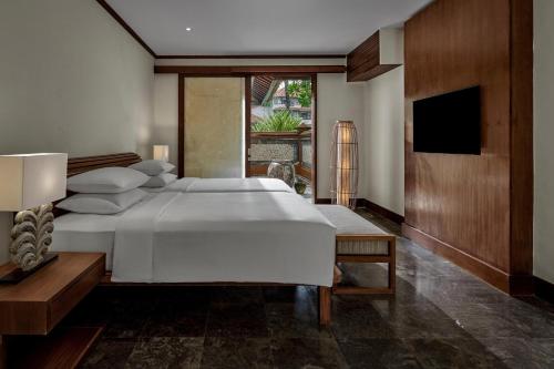 a bedroom with a large white bed and a television at Grand Hyatt Bali in Nusa Dua