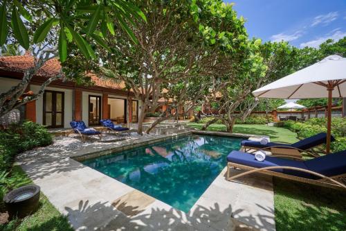 a swimming pool with chairs and an umbrella at Grand Hyatt Bali in Nusa Dua