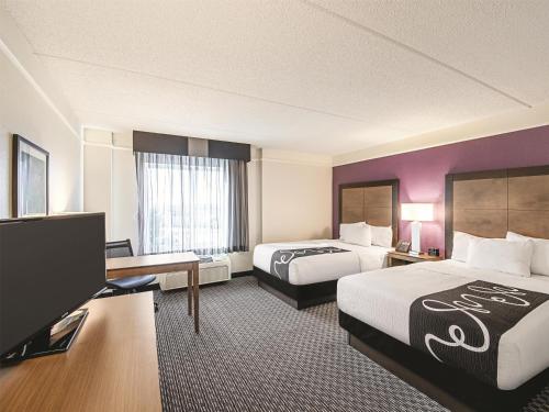 a hotel room with two beds and a flat screen tv at La Quinta by Wyndham Austin Airport in Austin