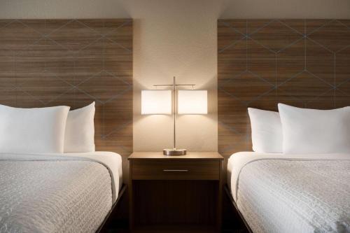 a hotel room with two beds and a cross on a night stand at La Quinta by Wyndham Shawnee in Shawnee