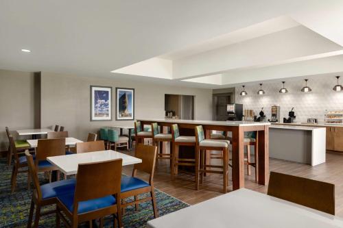 a restaurant with tables and chairs and a kitchen at La Quinta by Wyndham Shawnee in Shawnee