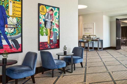 a waiting room with chairs and paintings on the wall at Hyatt Place Pena Station/Denver Airport in Denver