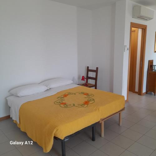 une chambre avec un lit avec une couverture jaune dessus dans l'établissement La casa dei nonni, à Villafranca di Verona