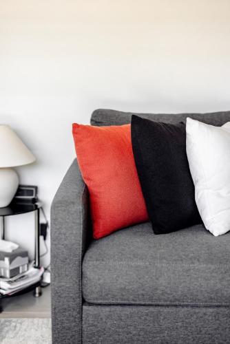 a gray couch with a red pillow on it at Mala Retreat, Shiraz Suite 5 Star Immaculate and Comfortable in East Maitland
