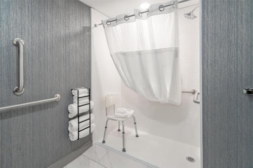 a bathroom with a shower with a chair and a shower curtain at DoubleTree by Hilton Sioux City in Sioux City