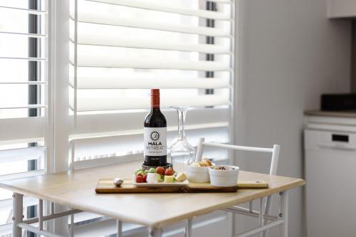 a bottle of wine and a plate of fruit on a table at Mala Retreat, Shiraz Suite 5 Star Immaculate and Comfortable in East Maitland