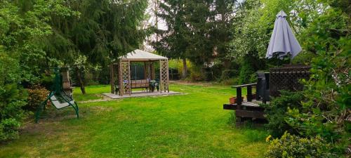 a garden with a gazebo and an umbrella at Domek rustykalny z sauną nad samym jeziorem in Leleszki