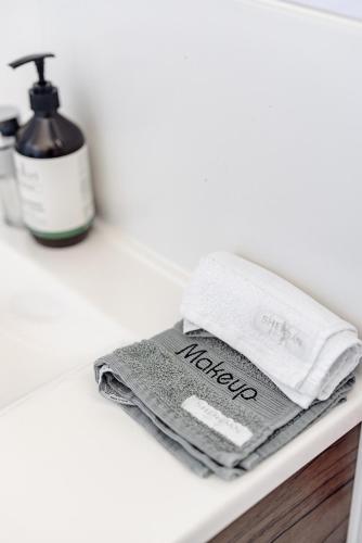 a pile of towels on a shelf with a bottle of soap at Mala Retreat, Shiraz Suite 5 Star Immaculate and Comfortable in East Maitland