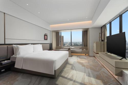 a bedroom with a white bed and a flat screen tv at Ramada by Wyndham Foshan Danzao in Huadu