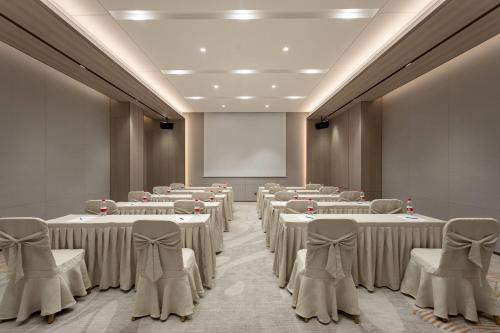 a room with rows of tables and chairs and a screen at Ramada by Wyndham Foshan Danzao in Huadu