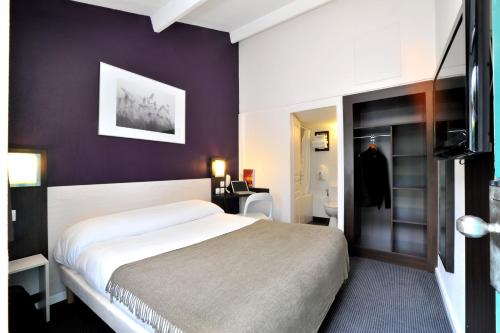 ダルディリーにあるBrit Hotel Lyon Nord Dardillyのベッドとバスルーム付きのホテルルームです。