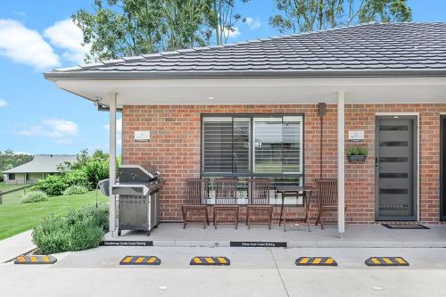 a brick house with a porch with a table and chairs at Mala Retreat, Shiraz Suite 5 Star Immaculate and Comfortable in East Maitland