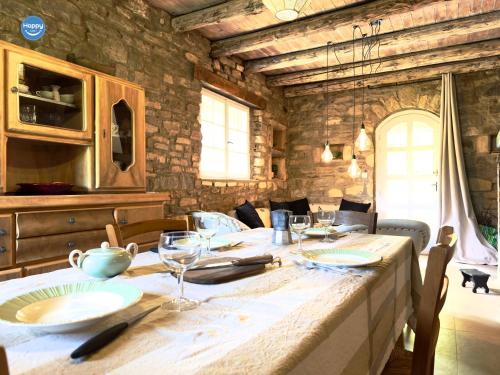 une grande table en bois avec des assiettes et des verres dans l'établissement Pura Vida Maison Ardéchoise, à Rochecolombe