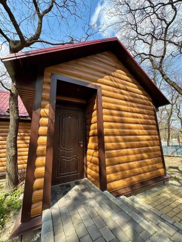 a log cabin with a door and a tree at Lake Park in Novomoskovsʼk